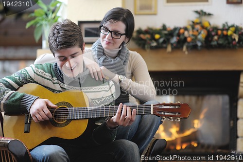 Image of Young romantic couple sitting and relaxing in front of fireplace