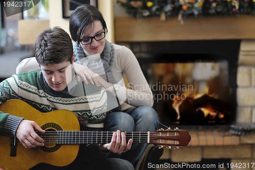 Image of Young romantic couple sitting and relaxing in front of fireplace