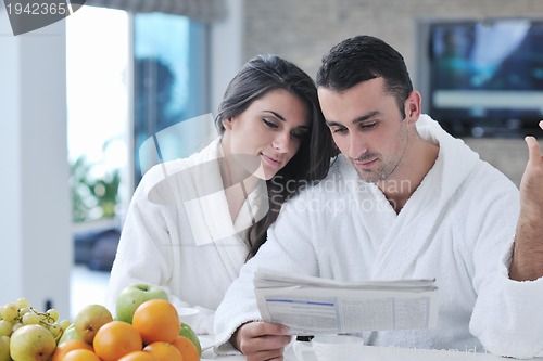 Image of Happy couple reading the newspaper in the kitchen at breakfast
