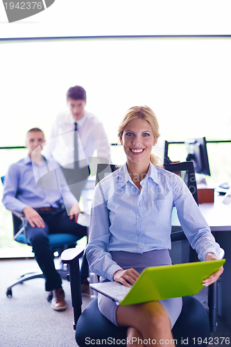 Image of business woman with her staff in background at office