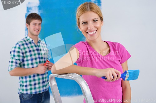 Image of happy couple paint wall at new home