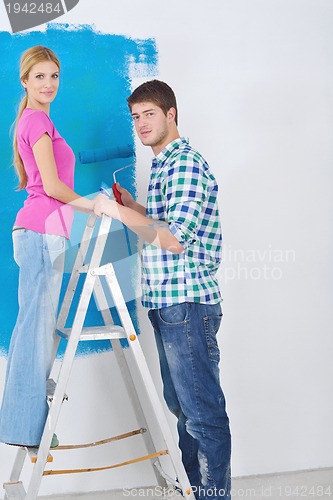 Image of happy couple paint wall at new home