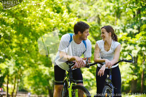 Image of Happy couple riding bicycle outdoors
