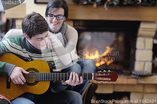 Image of Young romantic couple sitting and relaxing in front of fireplace