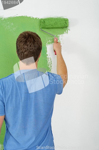 Image of handsome young man paint white wall in color