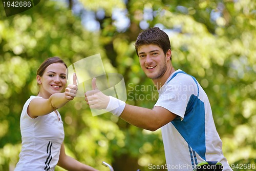 Image of Happy couple riding bicycle outdoors