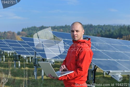 Image of engineer using laptop at solar panels plant field