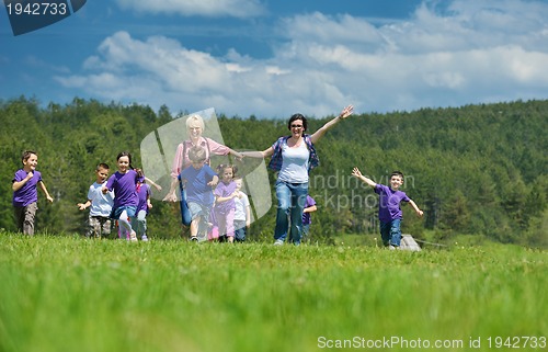 Image of happy kids group with teacher in nature