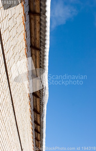 Image of Snow covered roof with icicles, deep blue sky at background