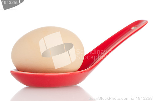 Image of Brown egg in a red ceramic spoon