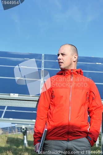 Image of engineer using laptop at solar panels plant field