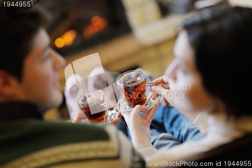 Image of Young romantic couple relax on sofa in front of fireplace at hom