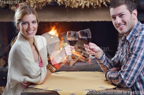 Image of Young romantic couple sitting and relaxing in front of fireplace