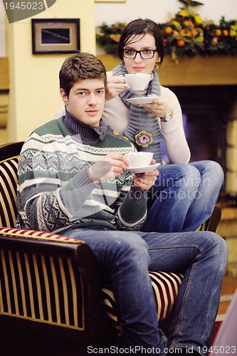 Image of Young romantic couple sitting and relaxing in front of fireplace
