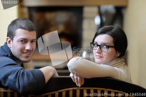 Image of Young romantic couple sitting and relaxing in front of fireplace