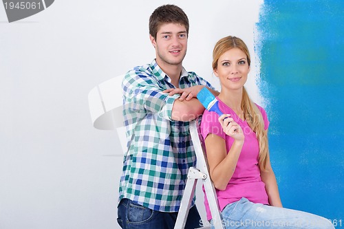 Image of happy couple paint wall at new home