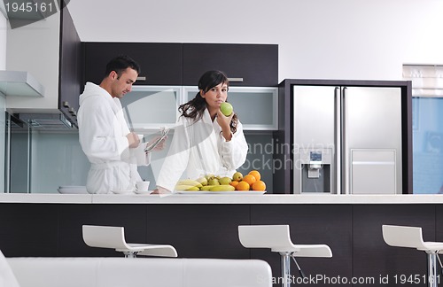 Image of Happy couple reading the newspaper in the kitchen at breakfast