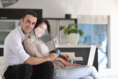Image of joyful couple relax and work on laptop computer at modern home