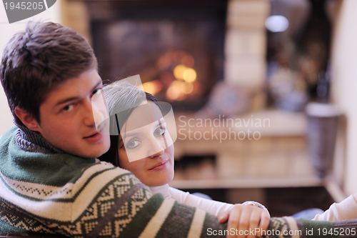 Image of Young romantic couple relax on sofa in front of fireplace at hom