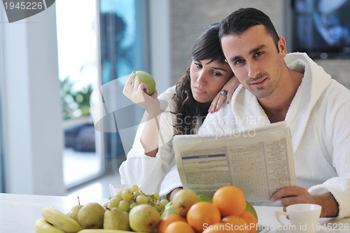 Image of Happy couple reading the newspaper in the kitchen at breakfast