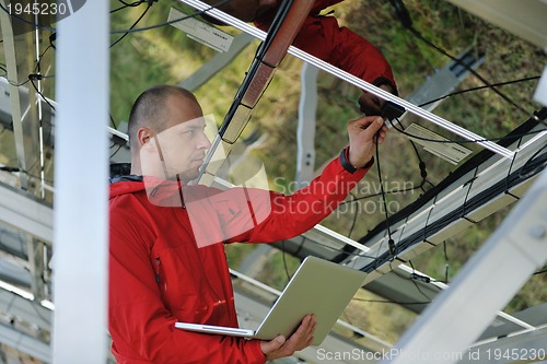 Image of engineer using laptop at solar panels plant field