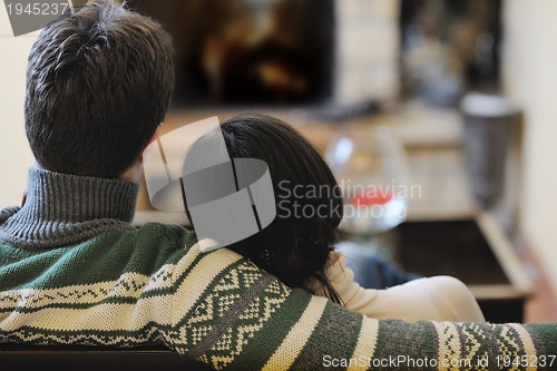 Image of Young romantic couple sitting and relaxing in front of fireplace