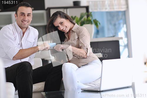 Image of joyful couple relax and work on laptop computer at modern home