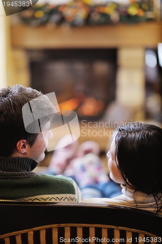 Image of Young romantic couple sitting and relaxing in front of fireplace