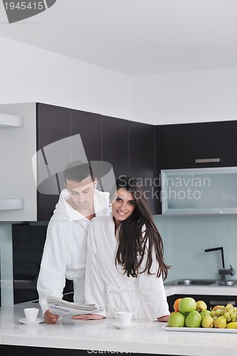 Image of Happy couple reading the newspaper in the kitchen at breakfast