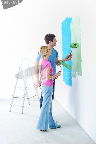 Image of happy couple paint wall at new home