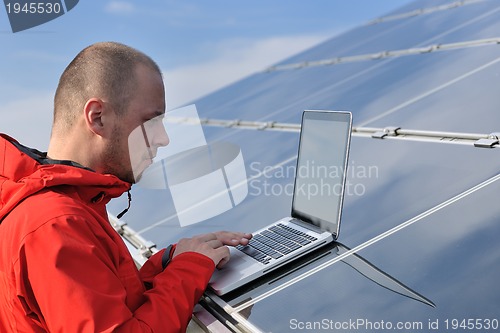 Image of engineer using laptop at solar panels plant field