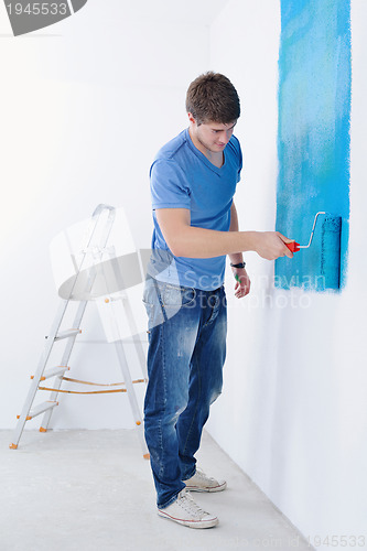 Image of handsome young man paint white wall in color