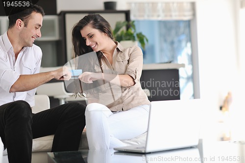 Image of joyful couple relax and work on laptop computer at modern home