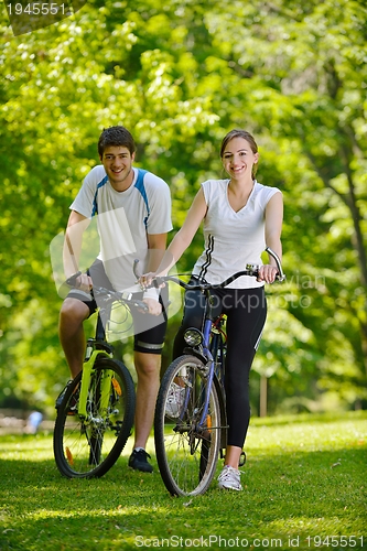 Image of Happy couple riding bicycle outdoors