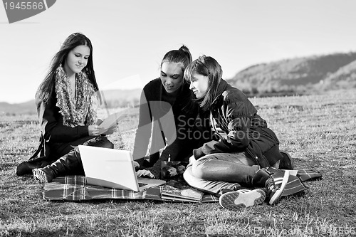 Image of group of teens working on laptop outdoor