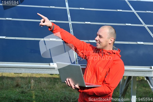 Image of engineer using laptop at solar panels plant field