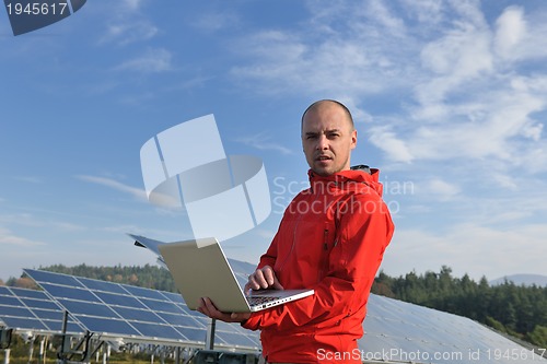 Image of engineer using laptop at solar panels plant field