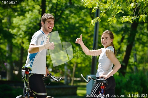 Image of Happy couple riding bicycle outdoors