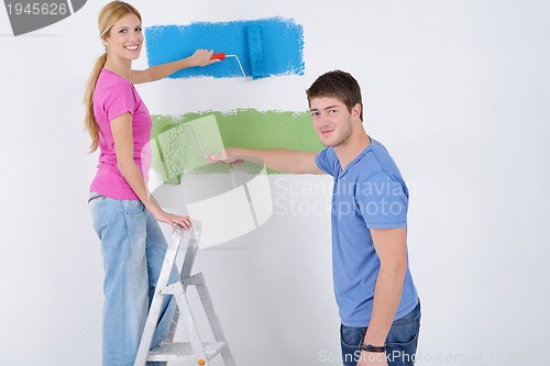 Image of happy couple paint wall at new home