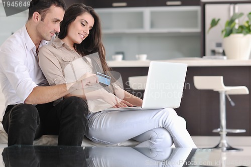 Image of joyful couple relax and work on laptop computer at modern home