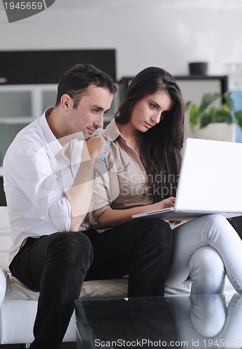 Image of joyful couple relax and work on laptop computer at modern home