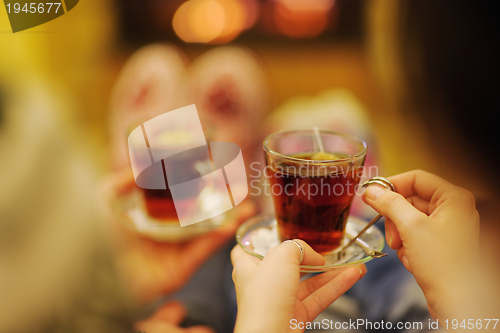 Image of Young romantic couple sitting on sofa in front of fireplace at h