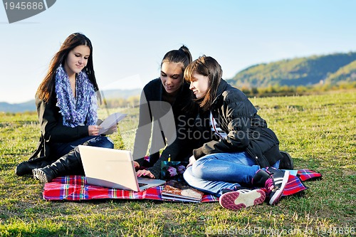 Image of group of teens working on laptop outdoor