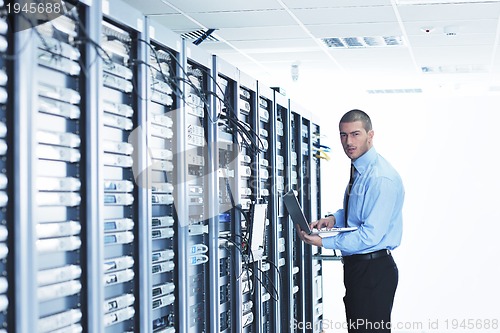 Image of businessman with laptop in network server room