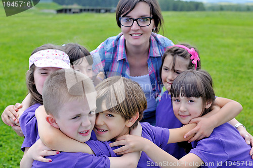 Image of happy kids group with teacher in nature