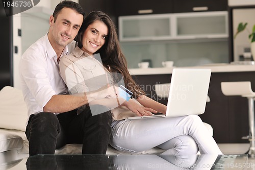 Image of joyful couple relax and work on laptop computer at modern home