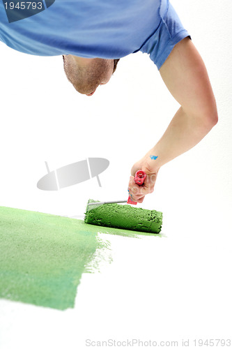 Image of handsome young man paint white wall in color