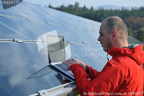 Image of engineer using laptop at solar panels plant field