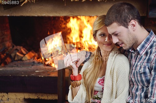Image of Young romantic couple sitting and relaxing in front of fireplace
