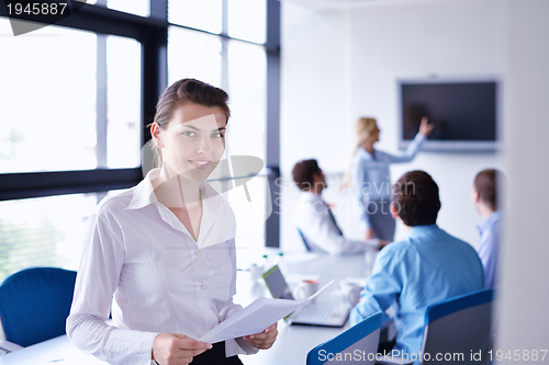 Image of business woman with her staff in background at office
